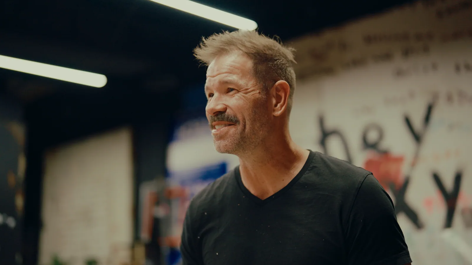 A painter laughing in his studio.