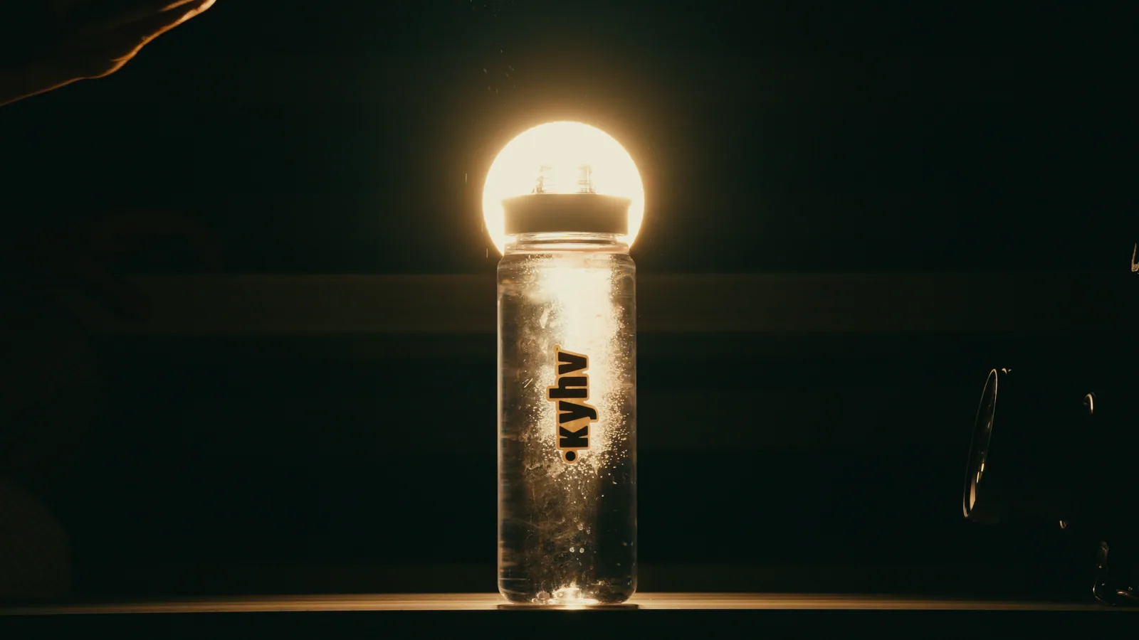 A water bottle lit from above in a dark room.